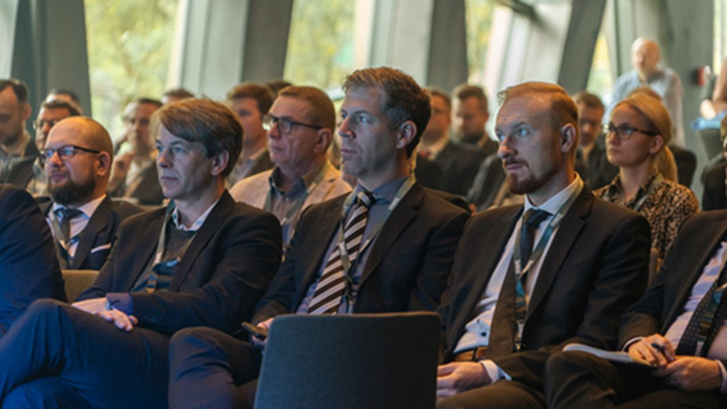 A group of men in suits sitting in a modern conference room, attentively listening to a presentation.