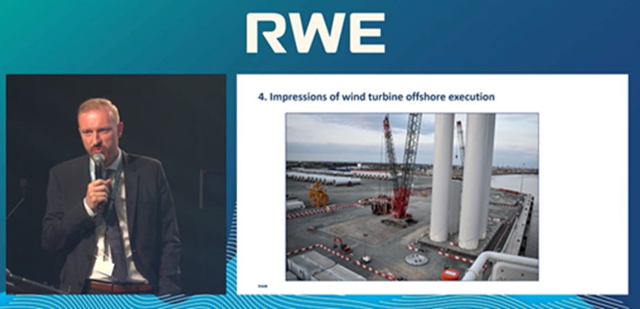 A presenter discussing wind turbine offshore execution with a project image behind, featuring cranes and turbine components.